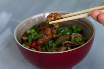 Traditional asian dish with rise and wok roasted meat, vegetables and mushrooms. Top view with space for text