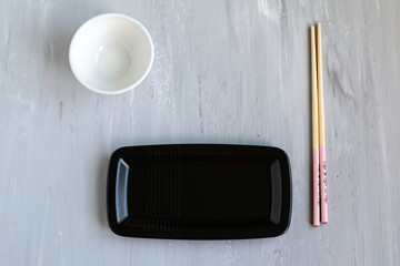 Traditional asian cutlery with plate, bowl for soy sauce bamboo sticks. Concept. With space for text
