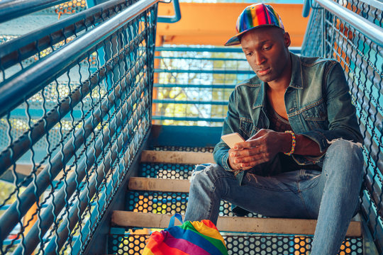 Young man in jean jacket and rainbow baseball cap