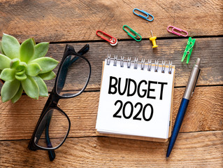 Budget 2020 concept. Top view of notepad with word Budget 2020 on wooden background.