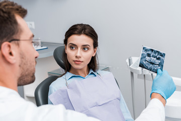 selective focus of attractive woman looking at dentist with x-ray