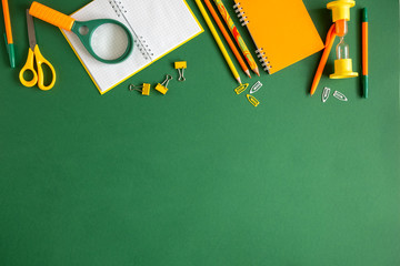 School accessories, pencils, pens on green background. Back to school. Flat lay, top view, copy space