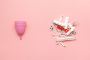 Reusable silicone menstrual cup and heap of tampons trash comparison on a soft pink background. Modern female intimate alternative gynecological hygiene. Eco zero waste concept