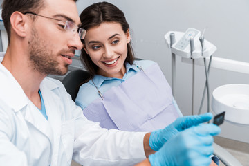 selective focus of handsome dentist in glasses holding x-ray near attractive woman