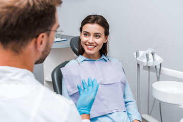 selective focus of attractive woman looking at dentist in clinic