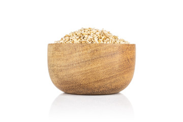 Lot of whole unpeeled sesame seeds in wooden bowl isolated on white background