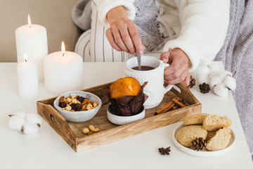 Girl drinks hot tea with cookies, nuts, cupcake