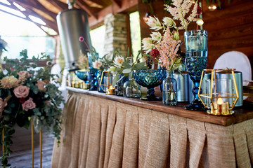 Table bride and groom at the wedding Banquet. Wedding floristry. Brown wooden screen. Tablecloth from simple tissue. Blue glass, hydrangeas , roses and cereals.