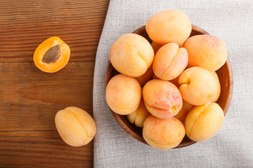 Naklejka na ściany i meble Fresh orange apricots in wooden bowl on wooden background. top view.