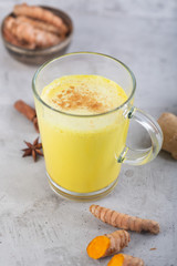 Golden turmeric milk on the gray background with ingredients