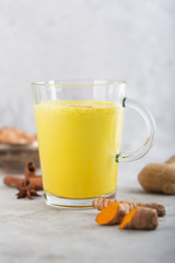 Golden turmeric milk on the gray background with ingredients