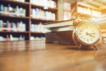 Alarm clock on the table, book, background blur, close-up shot
