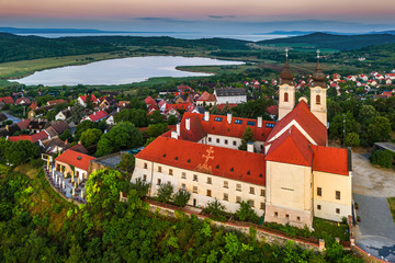 Obraz premium Tihany, Hungary - Aerial drone view of the famous Benedictine Monastery of Tihany (Tihany Abbey) with Inner lake and beautiful golden sunrise over Lake Balaton