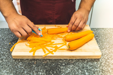 Close Up of Man Hands Peeling Carrots on Kitchen Counter