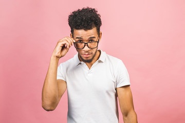 Fototapeta premium Soon to be startup owner or salesman. Portrait of cool and handsome african male student looking at camera smiling with eyeglasses isolated against pink background.