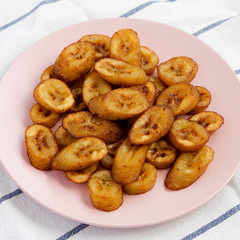Homemade fried plantains on a pink plate, side view. Close-up.