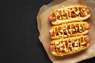 Homemade Detroit style chili dog on a black surface, view from above. Flat lay, top view, overhead....
