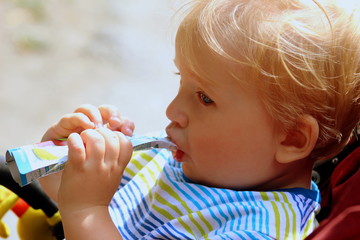 Toddler boy in a stroller eating baby food, food on the street, children's snack,