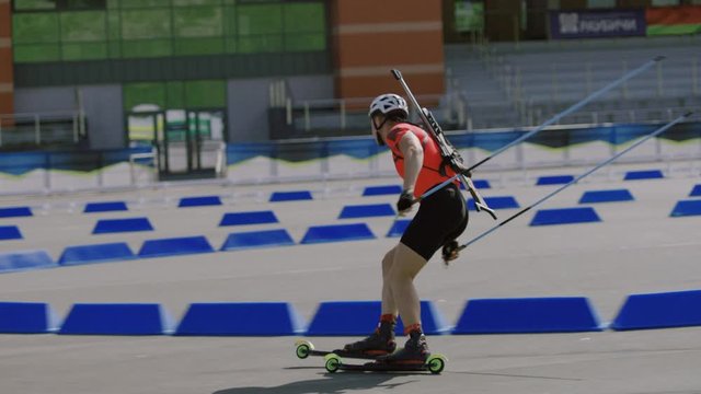 TRACKING SIDE VIEW Caucasian male professional biathlete roller skiing on a stadium during mid-season practice in summer. ARRI Alexa Mini with Cooke S4 prime lenses RAW graded footage