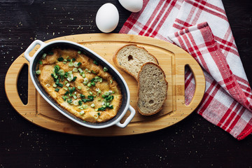 egg shaped casserole on the Board next to slices of bread, top view