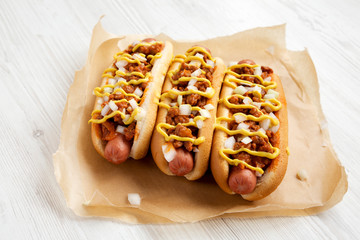 Homemade Detroit style chili dog on a white wooden background, low angle view. Close-up.