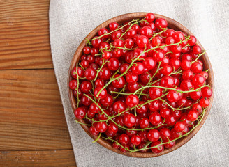 Fresh red currant in wooden bowl on wooden background. top view