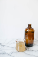 Amber Glass and Cup of Kombucha, Healthy Probiotic Drink, White and Marble Background, Copy Space