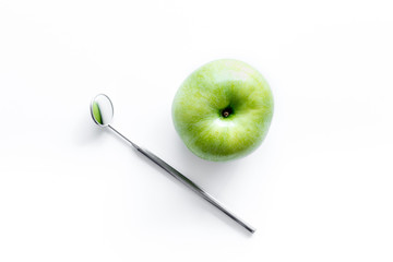mirror and apple on dentist desk with instruments white background top view