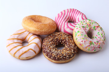 assorted delicious homemade doughnuts in the glaze, colorful sprinkles and nuts isolated on white background.