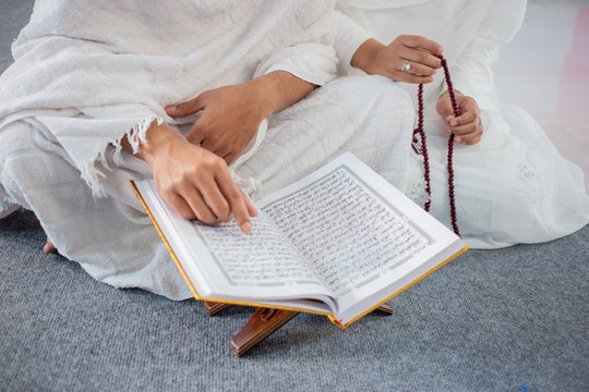 asian wife and husband praying with Al-Qur'an and tasbih in white traditional clothes