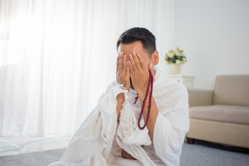 Muslim man praying while sitting in white traditional clothes