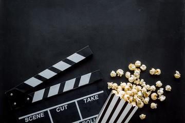Go to the cinema with popcorn and clapperboard on black background top view mock up