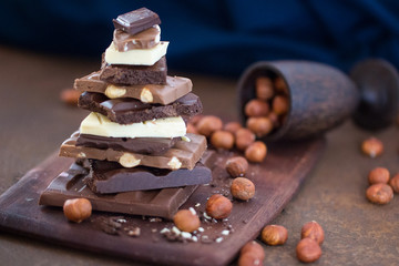 The different grades of chocolate put by the hill on a wooden board, with a filbert on a rusty metal surface. 