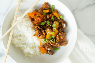 Sweet and Sour Ground Pork with Yellow and Orange Bell Peppers and Steamed Rice topped with Green Onions, Marble Background
