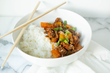 Sweet and Sour Ground Pork with Yellow and Orange Bell Peppers and Steamed Rice topped with Green Onions, Marble Background
