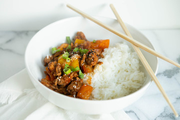 Sweet and Sour Ground Pork with Yellow and Orange Bell Peppers and Steamed Rice topped with Green Onions, Marble Background