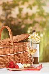 Picnic basket, wine and products on table outdoor