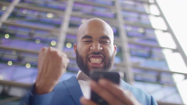 Smart city worker reacts positively to news on his phone, in slow motion