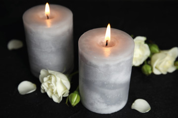 Fototapeta na wymiar Burning candles and beautiful flowers on black table