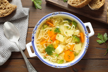 Dish of fresh homemade vegetable soup served on wooden table, flat lay