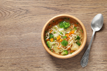 Bowl of fresh homemade vegetable soup served on wooden table, flat lay. Space for text