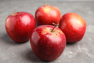 Ripe juicy red apples on grey table, closeup