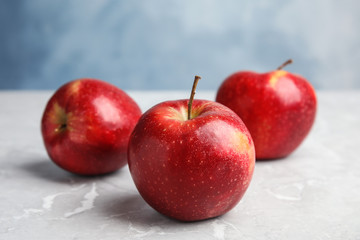 Ripe juicy red apples on grey table against blue background
