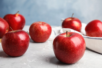 Ripe juicy red apples on grey table against blue background. Space for text