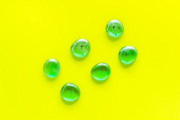 Shiny glass stones for decoration, creativity and craft on yellow background top view copyspace