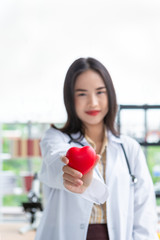 Asian nutritionist doctor woman showing red heart in right hand on laboratory room background