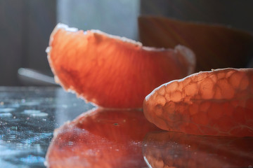 Individually peeled ruby red grapefruit on a reflective source.