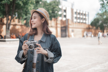 Fototapeta na wymiar Smiling woman traveler with backpack holding vintage camera on holiday in thapae gate landmark chiang mai thailand,relaxation concept, travel concept