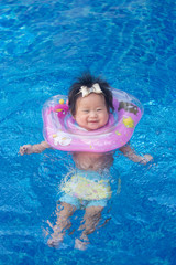 Baby swimming with neck swim ring in pool