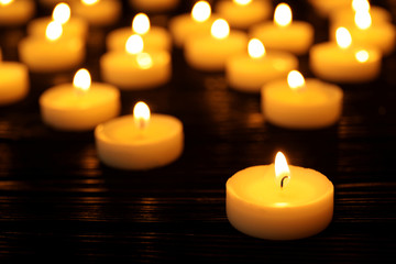 Many burning candles on table in darkness, space for text